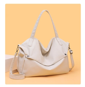 Detail of creamy white tote bag featuring lychee grain texture and metal rivet accents