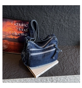 Detail of blue denim shoulder bag with multiple zippered pockets and adjustable strap