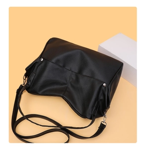 Close-up of black leather tote bag with silver rivets and adjustable shoulder strap