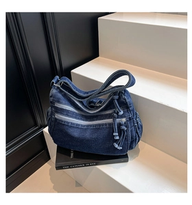 Close-up of deep blue denim bag showing three front zippers and side pocket details