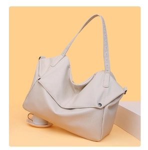 Detail of cream leather tote bag featuring lychee texture and metallic button accent