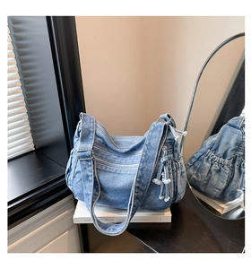 Detail of vintage blue denim tote bag with zipper pockets and tassels on white books