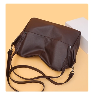 Detailed macro view of the dark brown leather texture and silver rivets on the tote bag