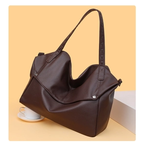 Detailed close-up of dark brown lychee grain leather tote bag with metal hardware