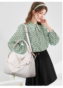 Detail of cream white leather tote bag featuring metal buckle and litchi grain texture