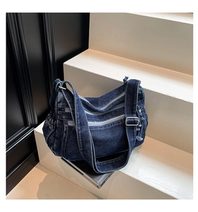 Detail of dark blue washed denim shoulder bag with multiple zippers and wide strap