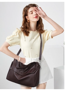 Detail of dark brown leather tote bag with natural texture and adjustable strap on model