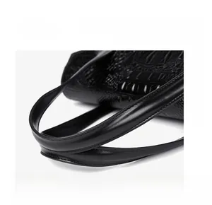 Close-up of durable cowhide leather handle and elegant crocodile pattern on black tote