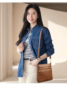 Dettaglio borsa a tracolla marrone motivo pietra con tre zip su outfit in denim