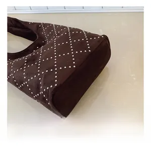 Dettaglio borsa a secchiello punk in pelle scamosciata marrone scuro con borchie silver