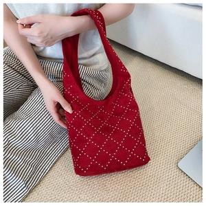 Detail of red suede bucket bag with silver metal rivets in diamond pattern