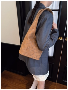 Close-up of brown suede bucket bag with silver rivet studs and a wide shoulder strap