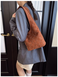 Close-up of a terracotta suede bucket bag with silver studs in a diamond lattice pattern