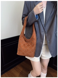 Close-up of brown suede hobo bag with silver metal studs in a diamond pattern