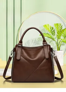 Detail of dark brown lychee leather handbag featuring large X-stitched seams and silver zippers