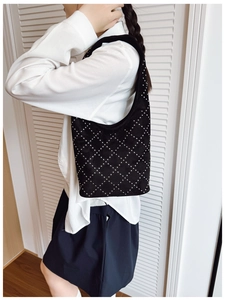 Detail of black studded bucket bag with silver rivet diamonds on matte suede surface