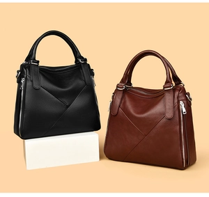 Detail view of black and brown tote bags showing lychee grain leather and V-shaped stitching