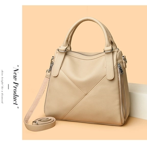 Detail view of beige lychee texture tote with triangle stitching and metal zipper accents