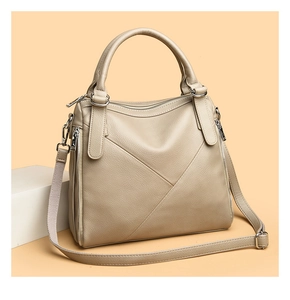 Detail of beige leather handbag with triangular stitching and silver zippers