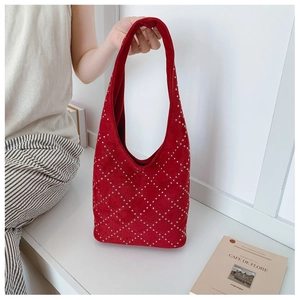 Dettaglio della borsa tote in pelle scamosciata rossa con borchie argentate e stile retrò