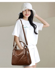 Detail of dark brown lychee leather handbag with precise stitching and metal zipper