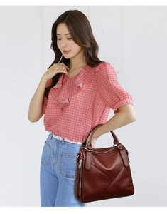 Deep reddish brown leather handbag with geometric stitching shown on a model
