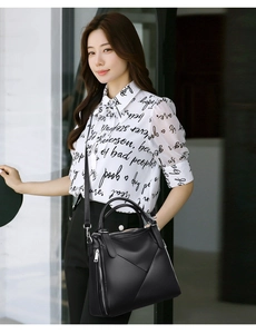 Detail of black textured leather handbag featuring geometric stitching and side zipper