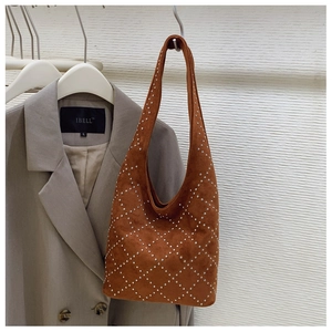 Macro detail of brown suede hobo bag featuring silver rivets and diamond lattice pattern