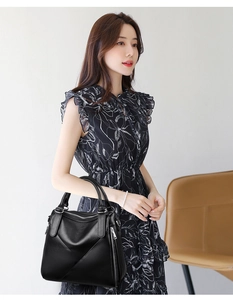 Detail of black pebbled leather tote with diagonal stitching and side zipper accents