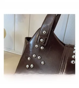 Détails d'un sac à bandoulière vintage marron foncé avec des clous métalliques argentés