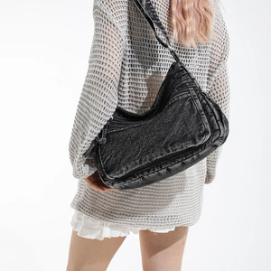 Retro black washed denim crossbody bag with multiple zip pockets shown on model