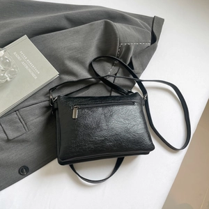 Minimalist black faux leather crossbody bag with lychee texture and rear zipper pocket