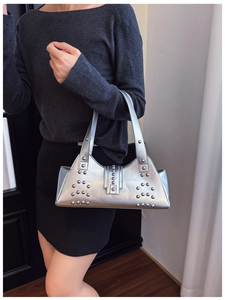 Détail d'un sac sous le bras argenté avec rivets décoratifs porté par un mannequin
