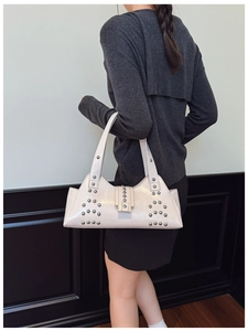 Détail du sac à bandoulière en cuir crème avec rivets argentés et boucle design