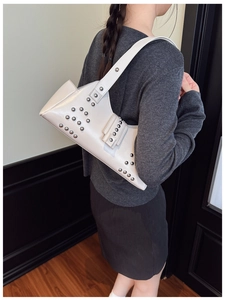 Détail du sac à bandoulière en similicuir blanc crème avec des clous métalliques argentés