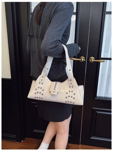 Détail du sac bandoulière vintage en cuir crème avec rivets argentés et fini brillant
