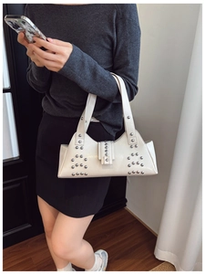 Détail d'un sac à bandoulière en similicuir blanc avec des rivets argentés et une boucle
