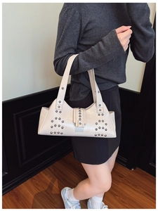 Détail du sac à bandoulière en cuir ivoire orné de rivets argentés sur un sac chic