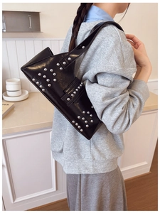Détail du sac sous le bras en cuir brillant noir avec rivets argentés style punk chic