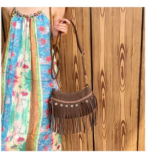 Détail du sac bandoulière marron foncé à franges avec bordure ethnique et breloques