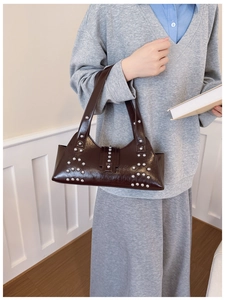 Détail du sac sous l'aisselle en cuir marron foncé avec rivets argentés par un mannequin