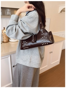 Détail d'un sac bandoulière marron foncé brillant avec rivets argentés et boucle rétro