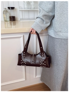 Détail d'un sac à bandoulière vintage en cuir huilé marron foncé avec des clous argentés