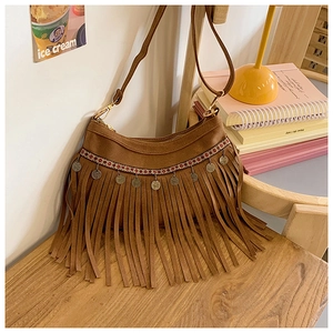 Détail du sac marron à franges avec pompons bohèmes et ornements en métal vintage