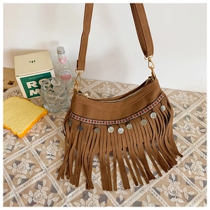 Gros plan du sac en daim marron avec franges, sangles tissées et breloques
