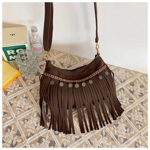 Détail du sac en daim marron avec broderies ethniques, pendentifs et longues franges