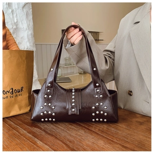 Détail du sac bandoulière vintage en cuir marron brillant avec rivets argentés
