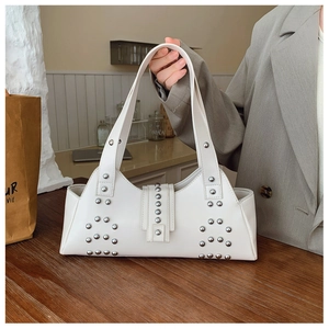 Détail du sac à épaule en cuir blanc avec rivets argentés porté par une personne