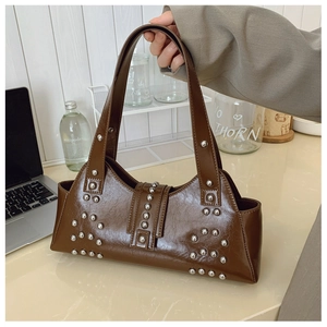 Détail du sac à bandoulière en cuir marron vintage avec clous argentés sur bureau