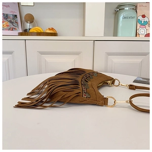 Gros plan sur un sac en daim marron avec franges bohèmes et rivets métalliques